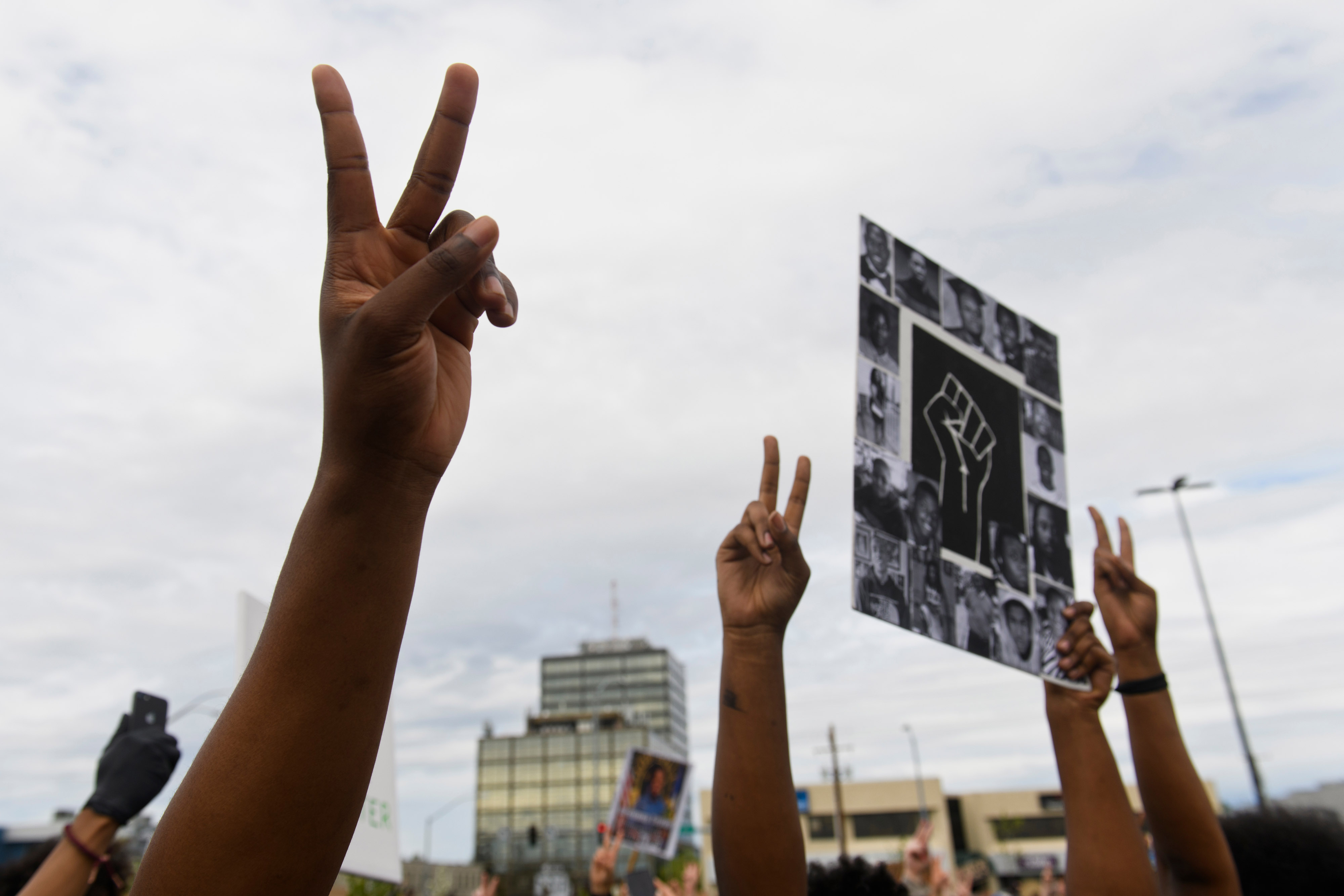 Crowd members raise peace signs in Midtown Anchorage, 2020