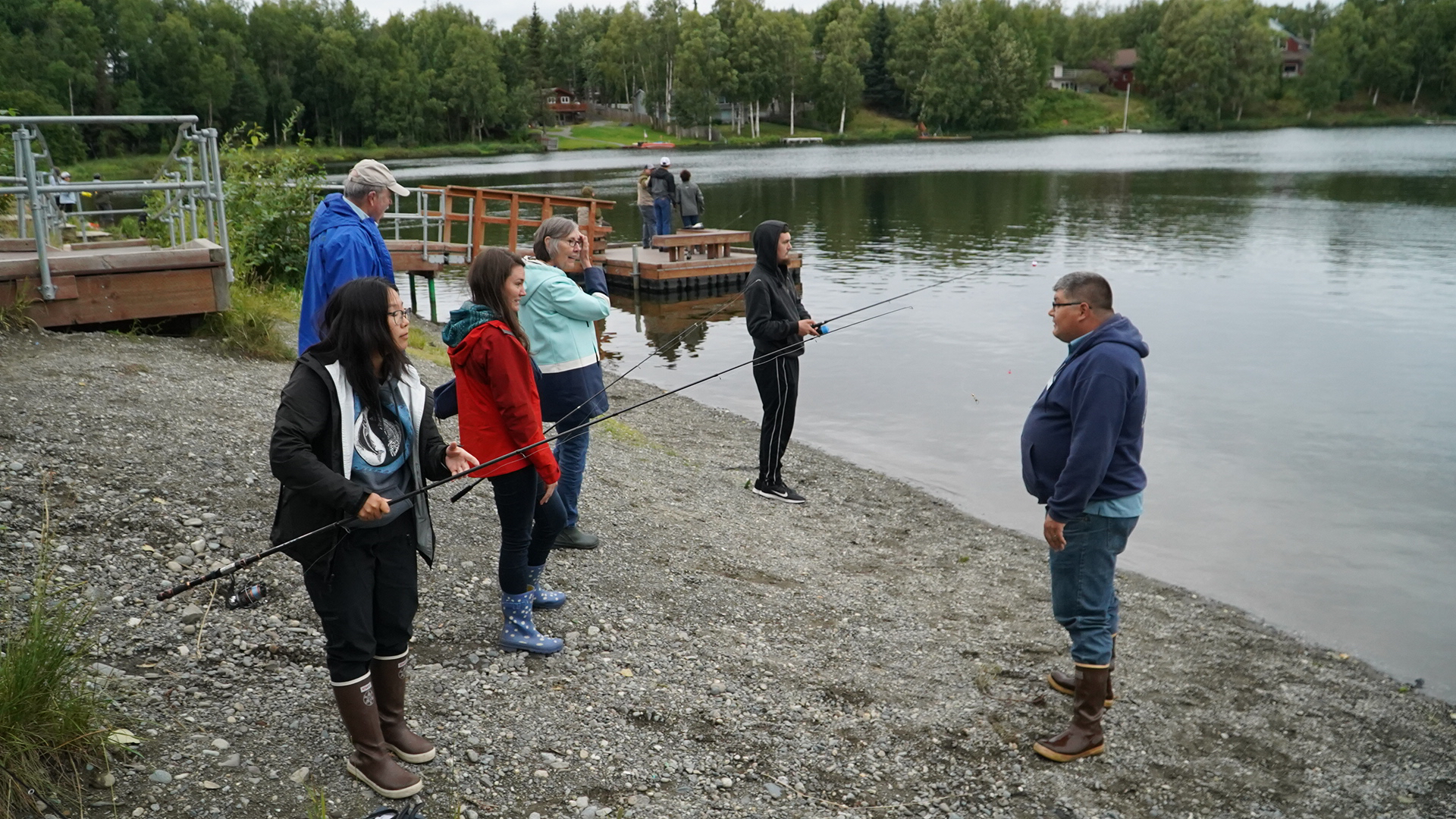 Fishermen gather on a lakeshore to learn about rainbow trout.