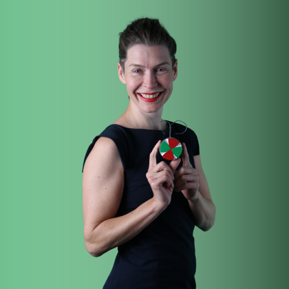 Woman posing in front of a green screen, holding a small and colorful object